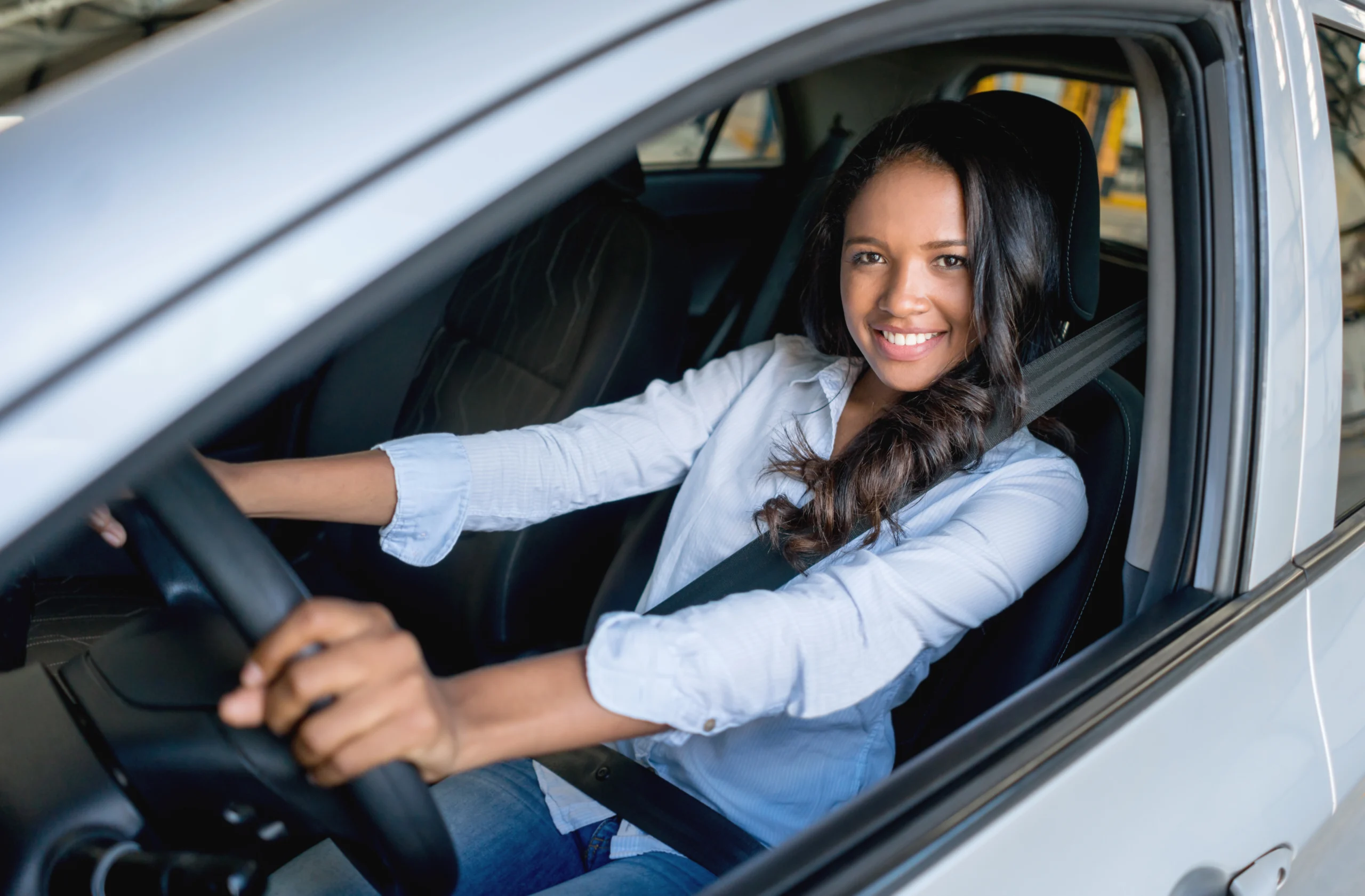 Femme au volant d'une voiture qui regarde le photographe en souriant